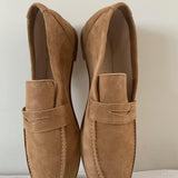 The Penny Loafer in Clove Suede against wall