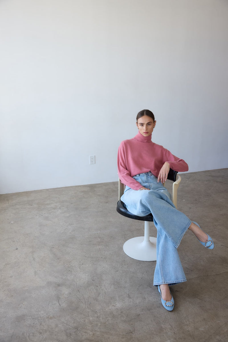 Woman wearing a pink sweater, light blue jeans, and baby blue suede Lady Heels.