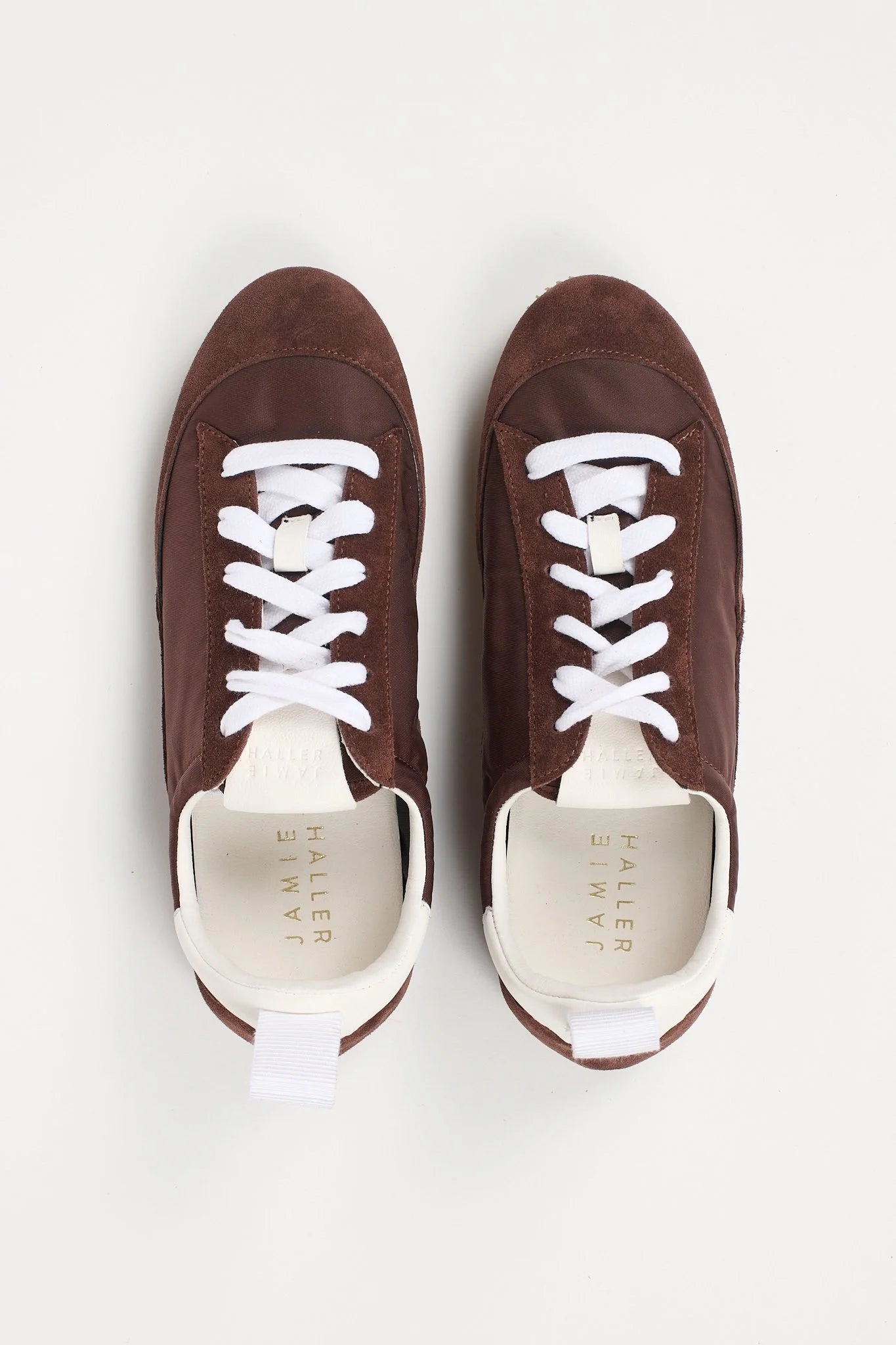 Pair of brown sneakers with white laces on a white background
