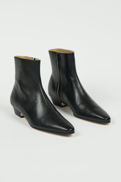 A pair of black leather ankle boots with pointed toes and low block heels, photographed on a clean white studio background.