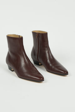 A pair of dark brown leather ankle boots with pointed toes and low block heels, shown from a three-quarters angle on a light gray background.