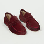 Pair of claret ponyhair penny loafers with moc toe stitching and leather soles, styled on a white background by Jamie Haller
