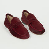 Pair of claret ponyhair penny loafers with moc toe stitching and leather soles, styled on a white background by Jamie Haller