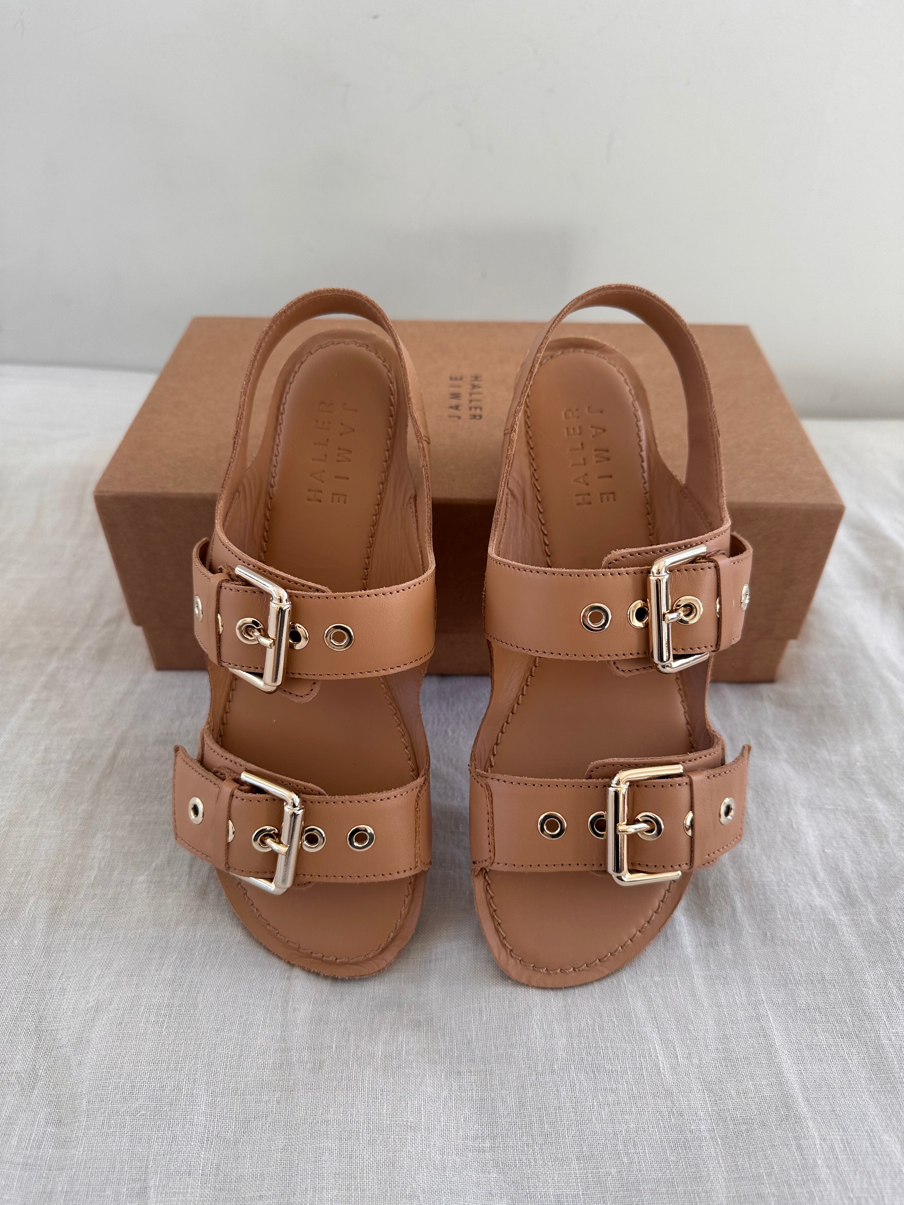 The Double Buckle Sandal in Bare on Bed Angled Down