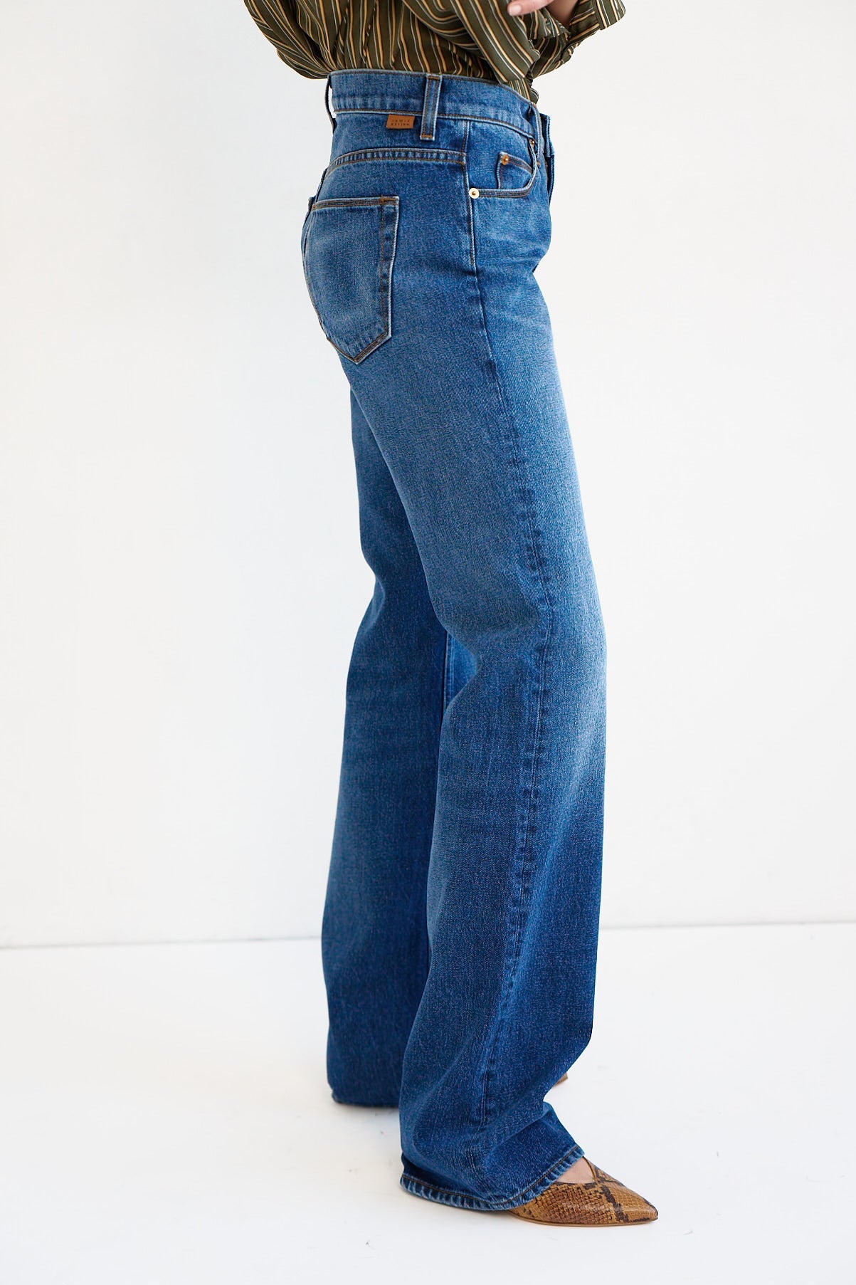 A person wearing a pair of high-waisted, wide-leg blue denim jeans, shown from the waist down against a plain white studio background.