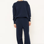 woman standing in all navy tracksuit in front of a white wall