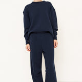 woman standing in all navy tracksuit in front of a white wall