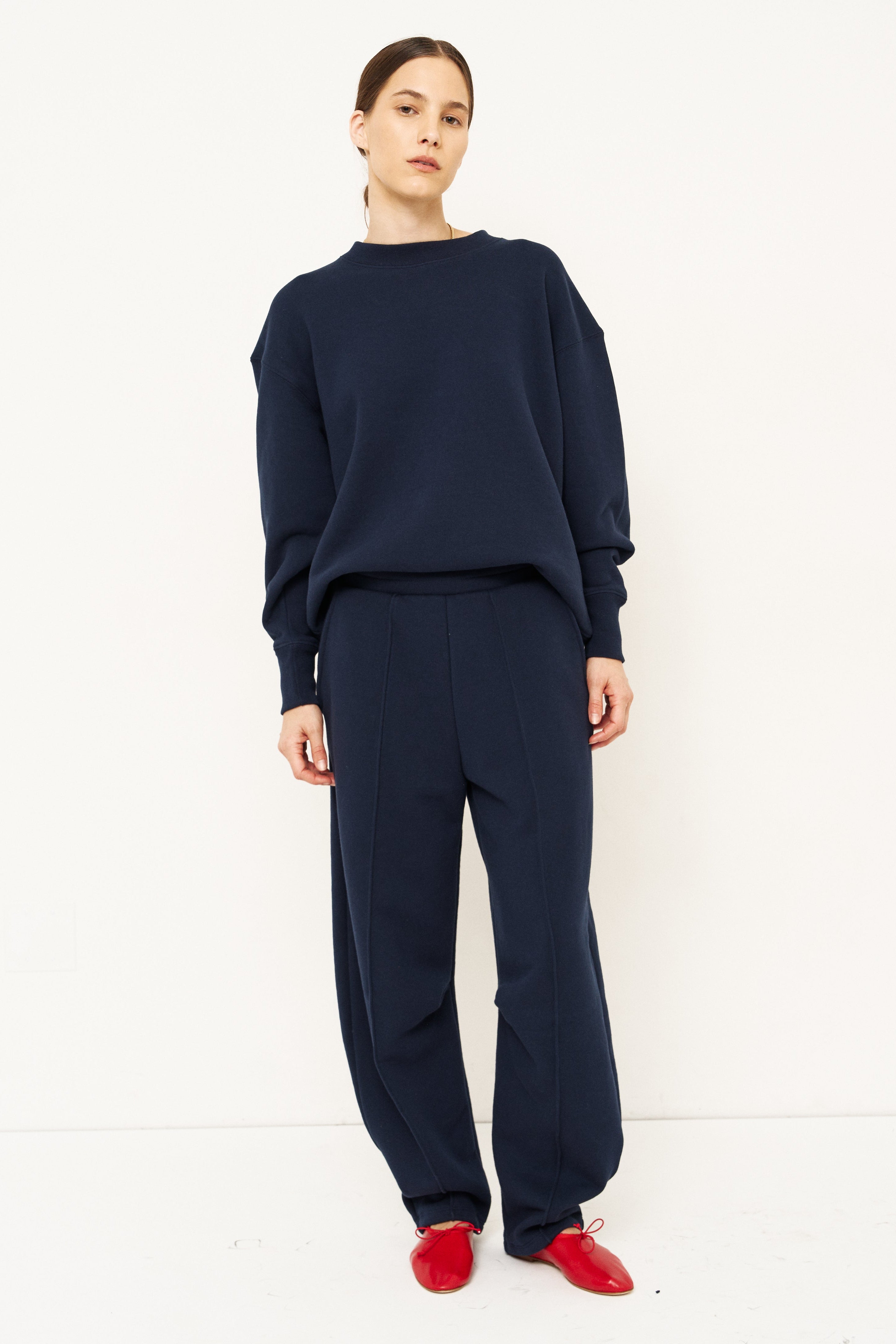 woman standing in all navy tracksuit in front of a white wall