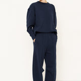 woman in navy sweatshirt and pants in front of a white wall