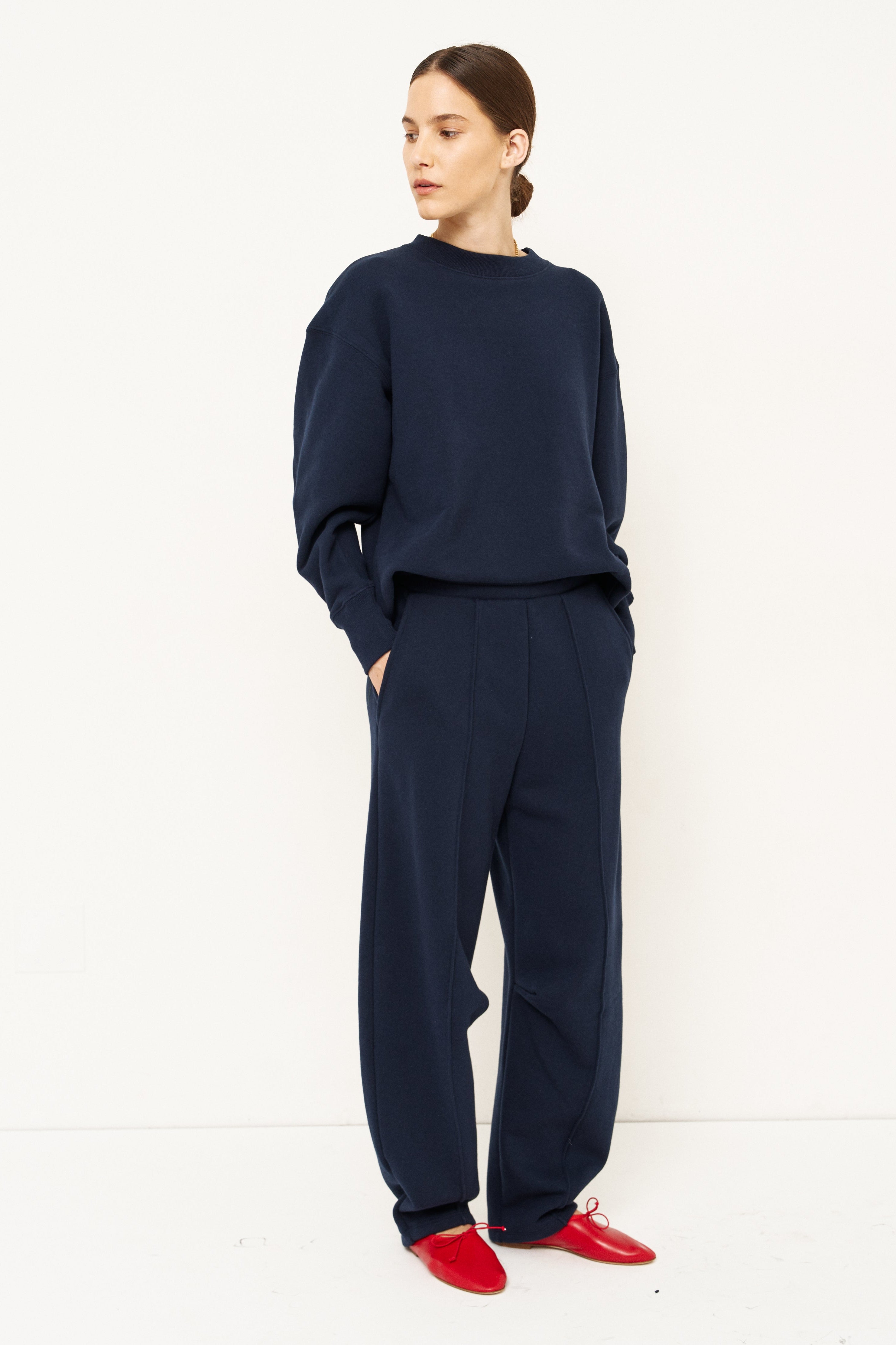woman in navy sweatshirt and pants in front of a white wall