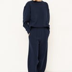 woman in a navy tracksuit in front a white wall