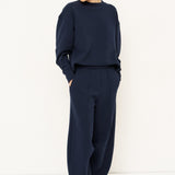 woman in a navy tracksuit in front a white wall