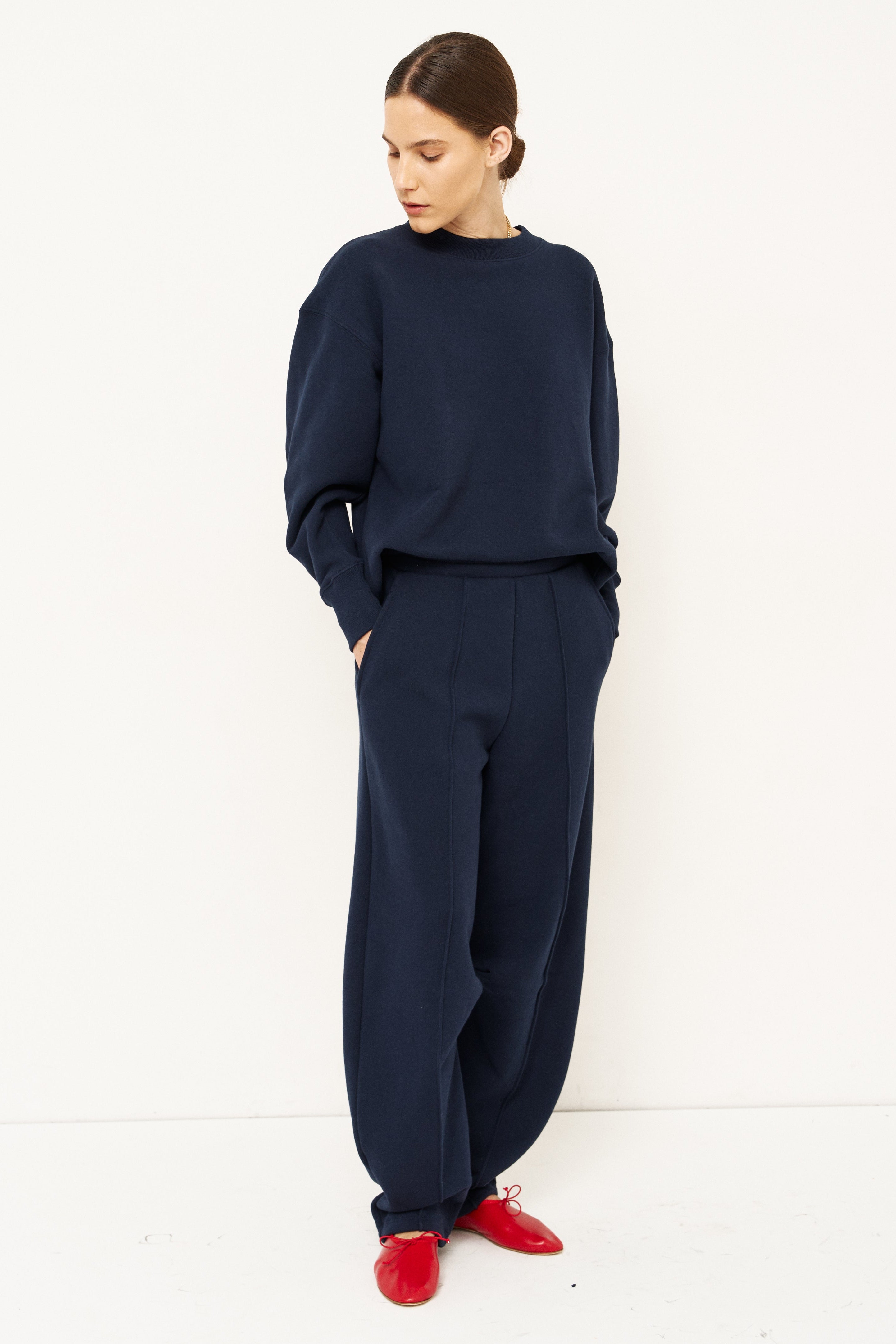 woman in a navy tracksuit in front a white wall