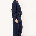 woman in navy sweatshirt and pants in front of a white wall