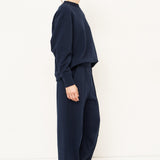 woman in navy sweatshirt and pants in front of a white wall