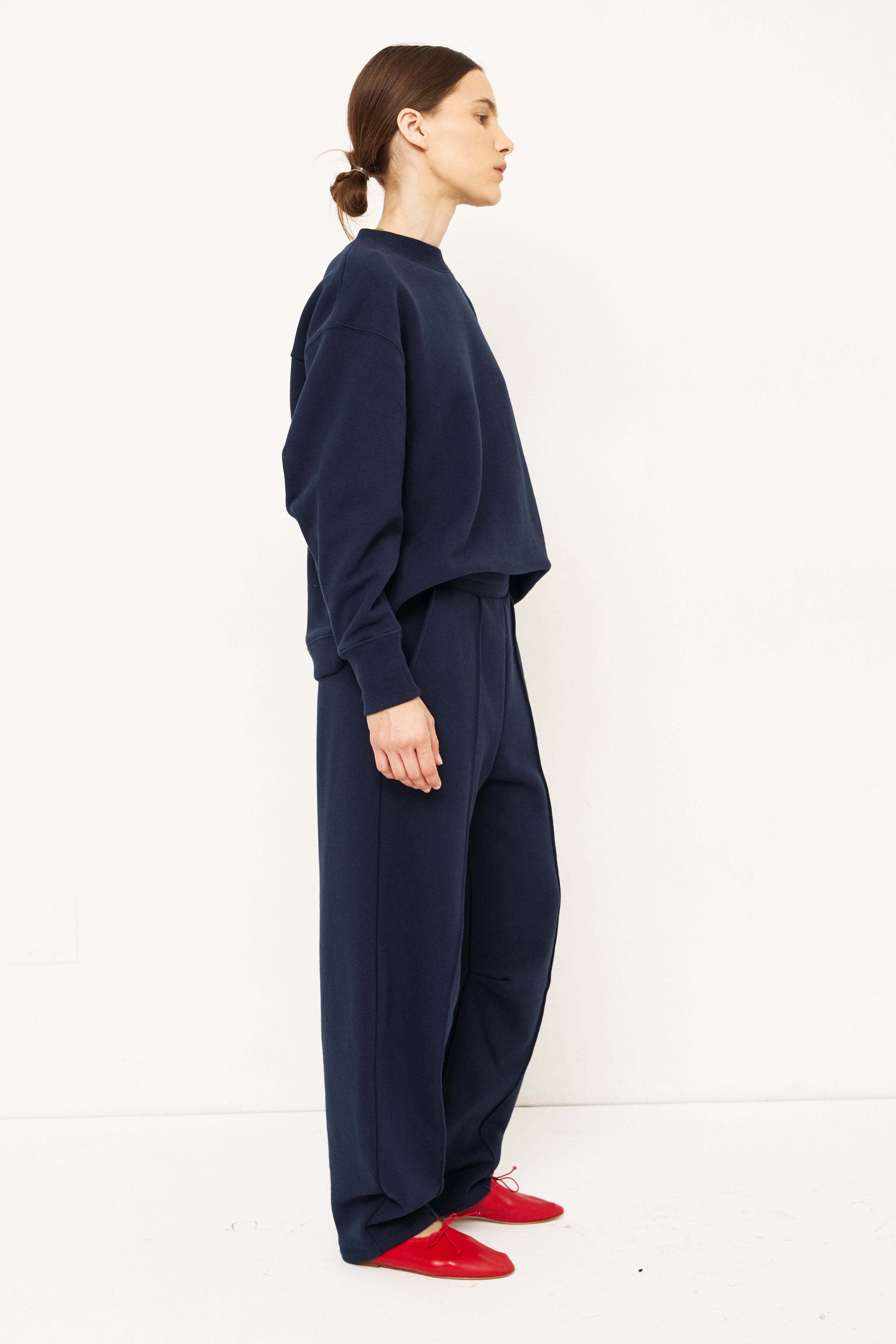 woman in navy sweatshirt and pants in front of a white wall