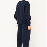 back side of woman standing in front of a white wall in a navy tracksuit