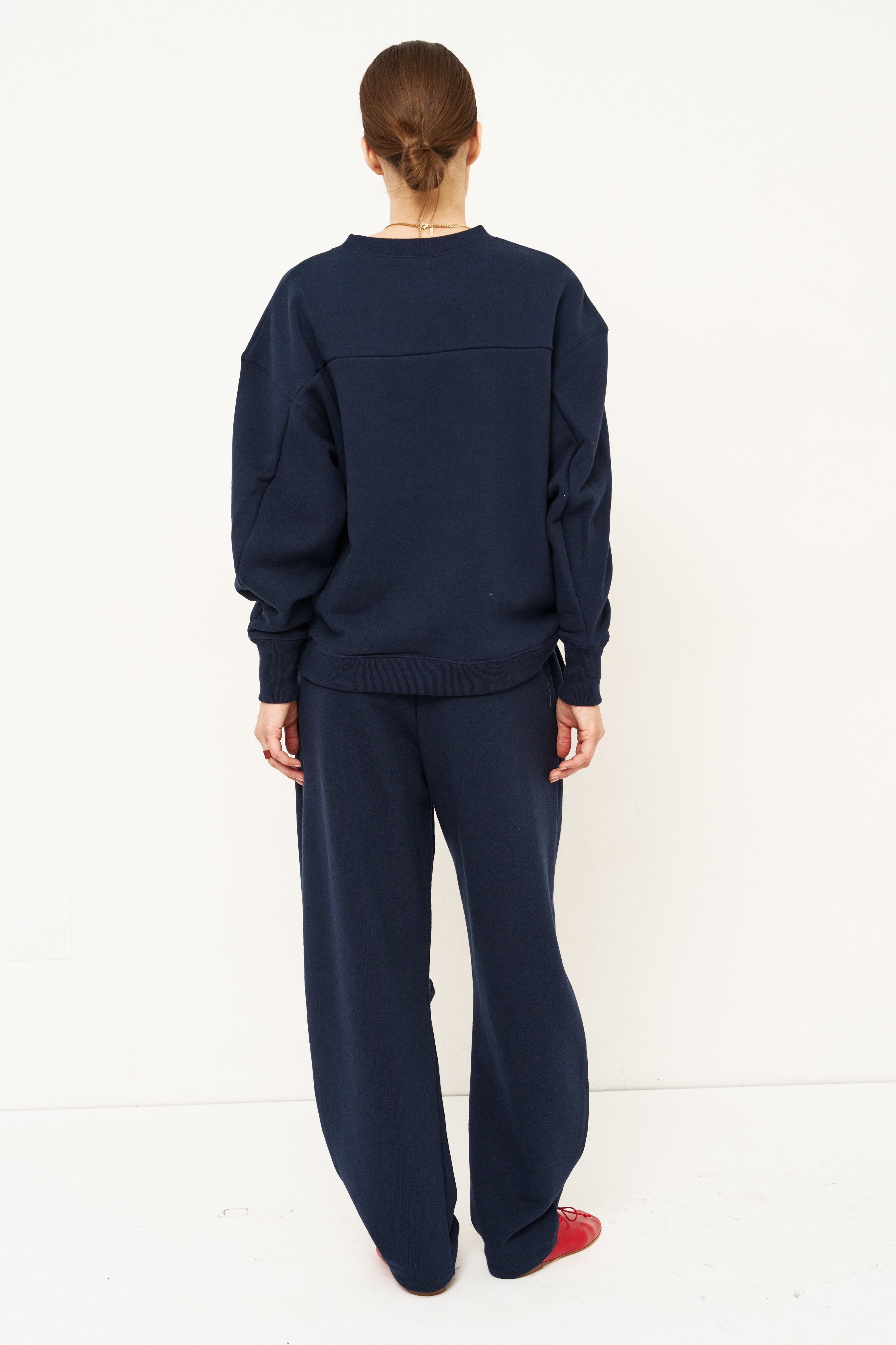 woman in navy sweatshirt and pants in front of a white wall