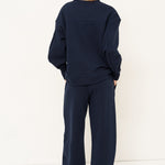 woman standing in all navy tracksuit in front of a white wall