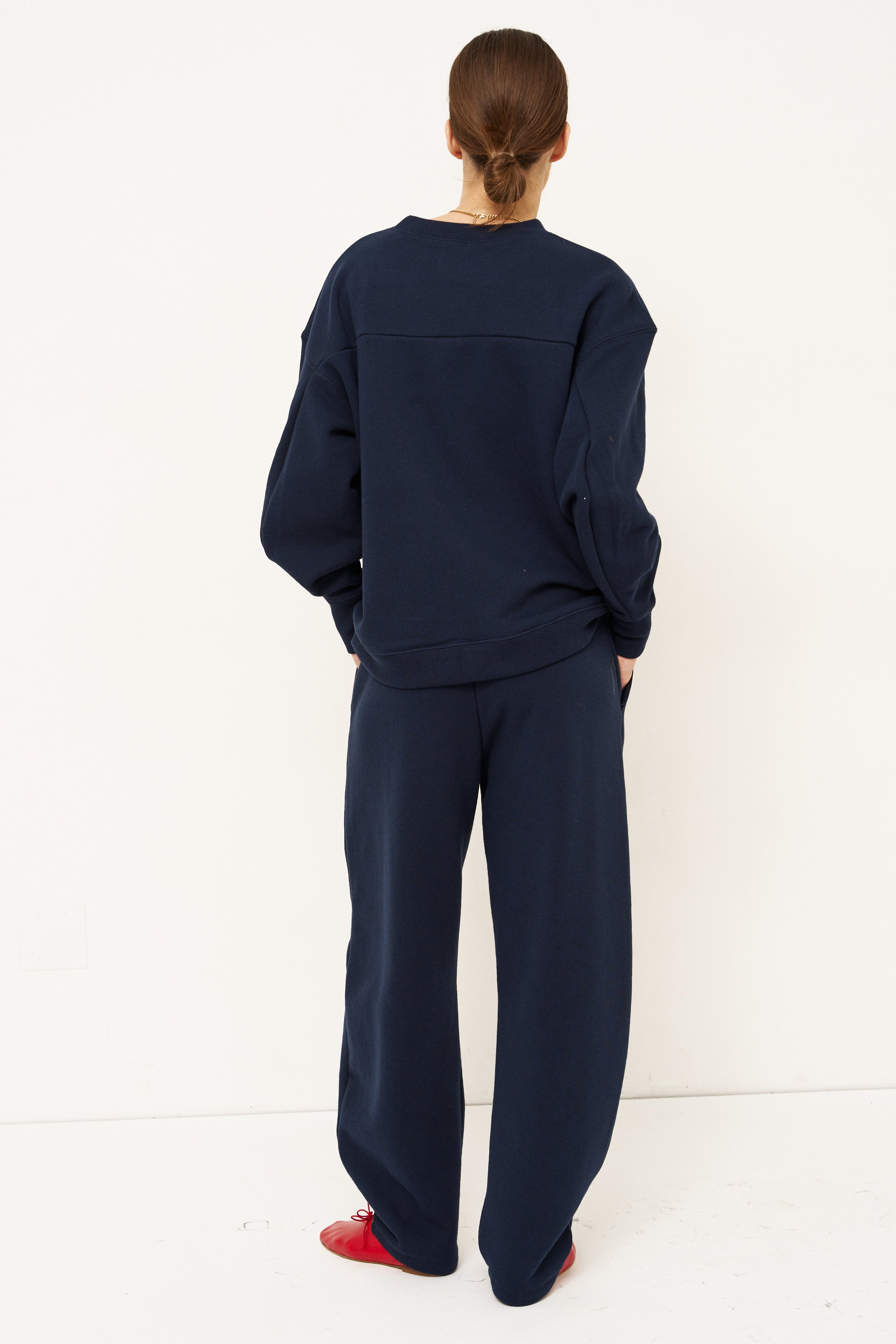 woman standing in all navy tracksuit in front of a white wall