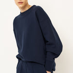 woman in navy tracksuit against a white wall