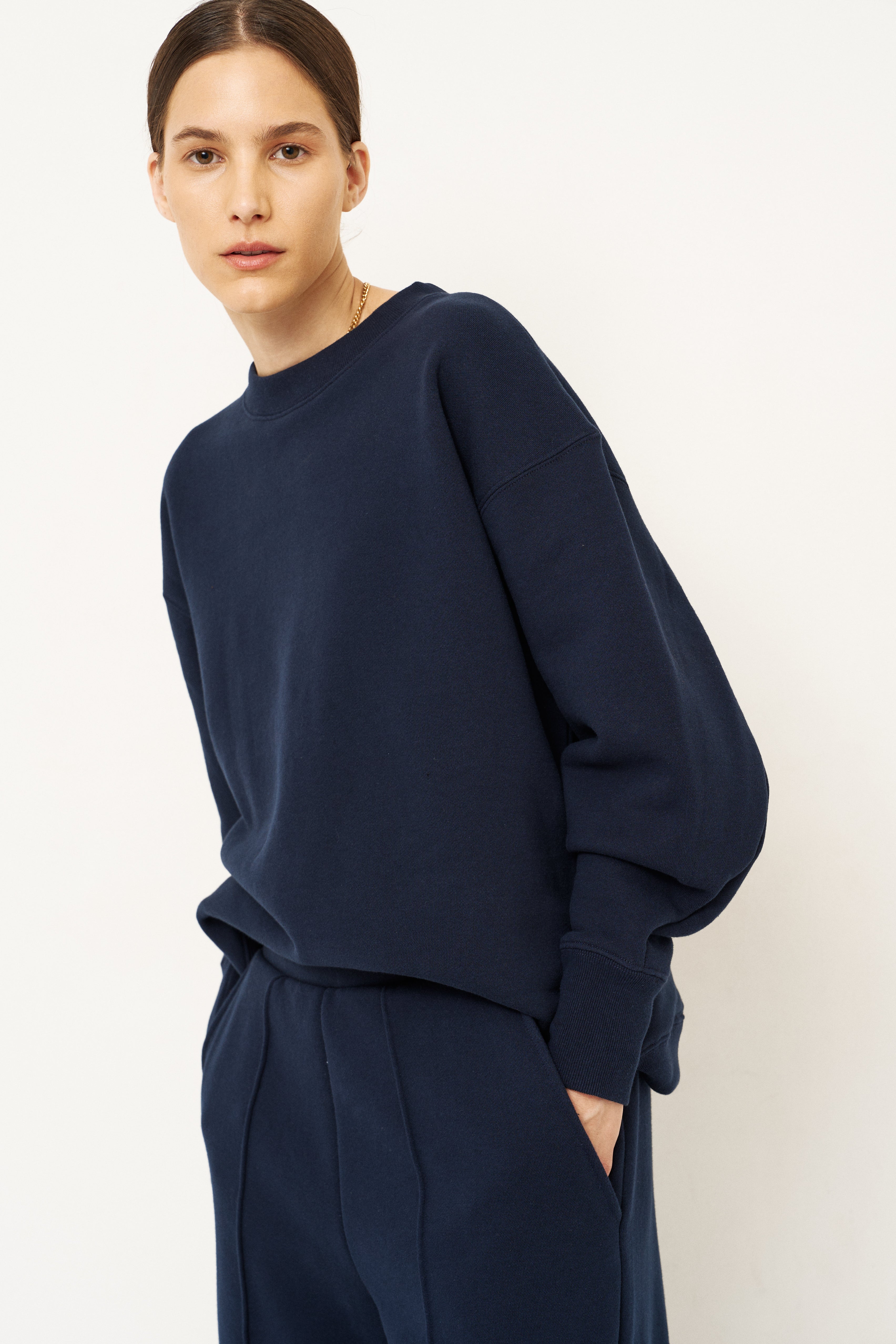 woman in navy tracksuit against a white wall