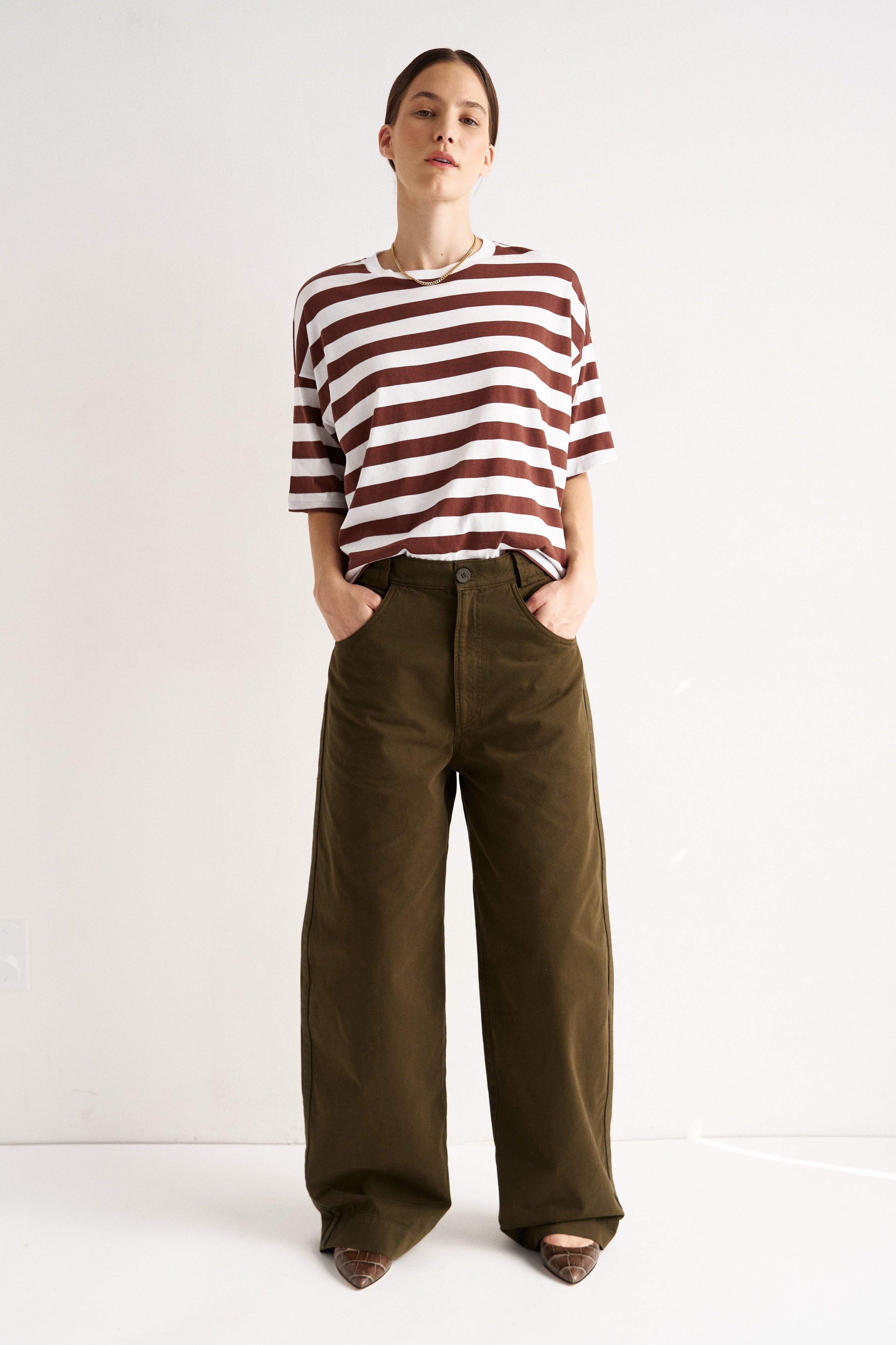 Person wearing a striped shirt and wide-leg pants on a white background