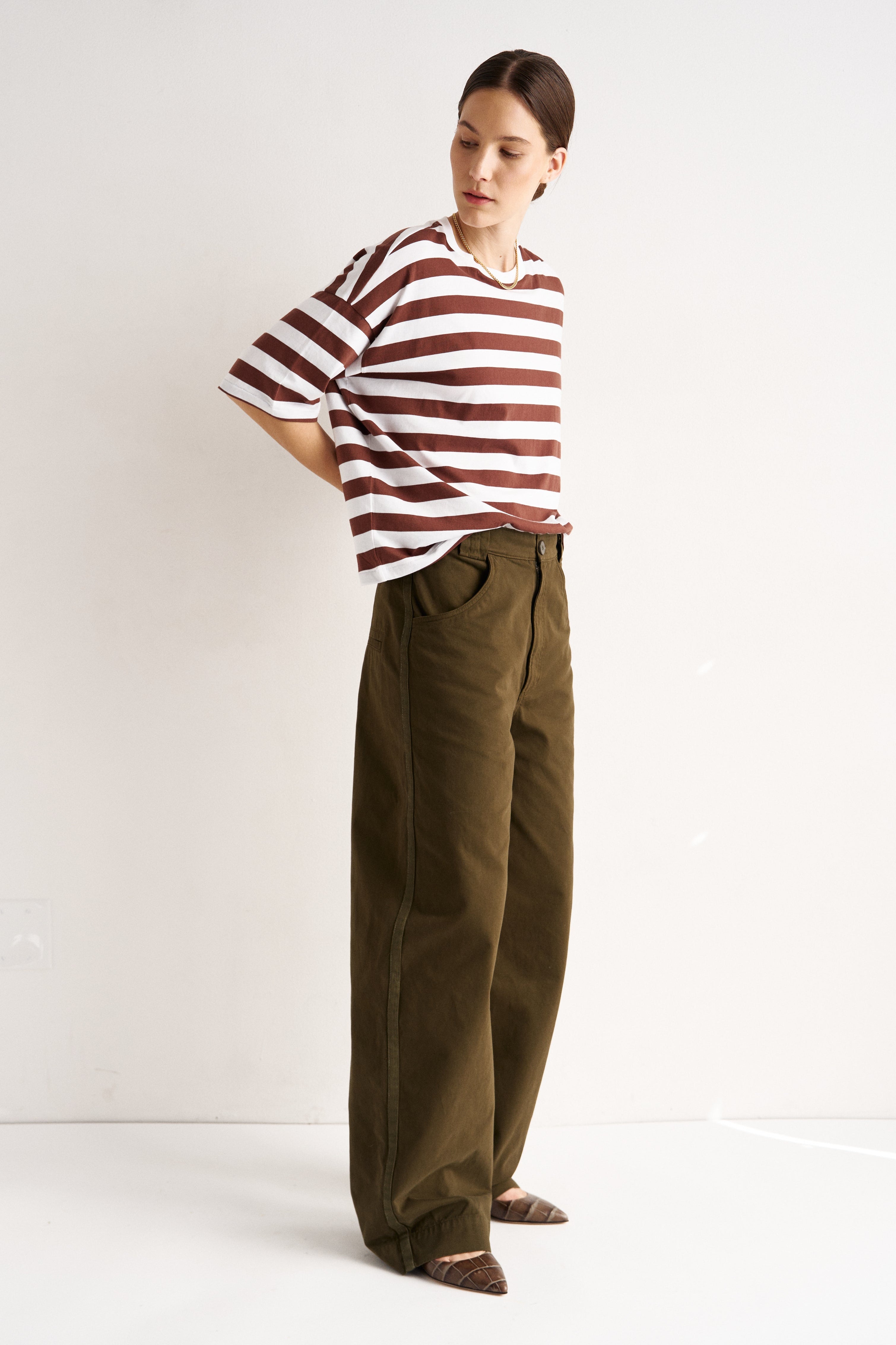 Person wearing a striped shirt and wide-leg pants on a white background
