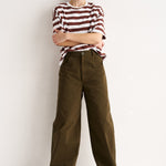 Woman wearing a striped shirt and brown pants against a white background