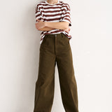 Woman wearing a striped shirt and brown pants against a white background