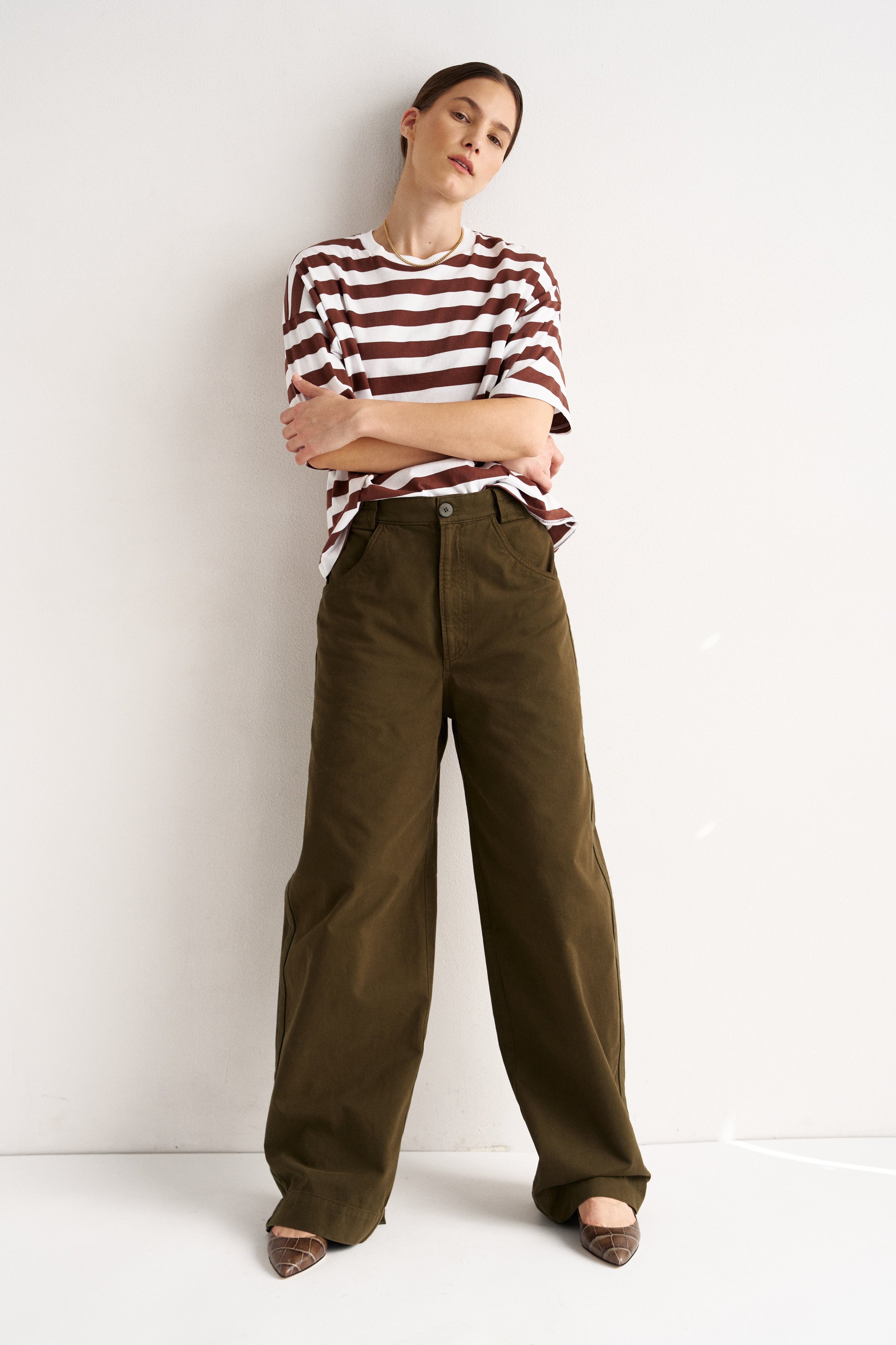 Woman wearing a striped shirt and brown pants against a white background