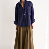 Woman wearing a navy striped shirt and brown skirt on a white background