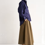 Person wearing a blue shirt and brown skirt on a white background
