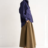 Person wearing a blue shirt and brown skirt on a white background