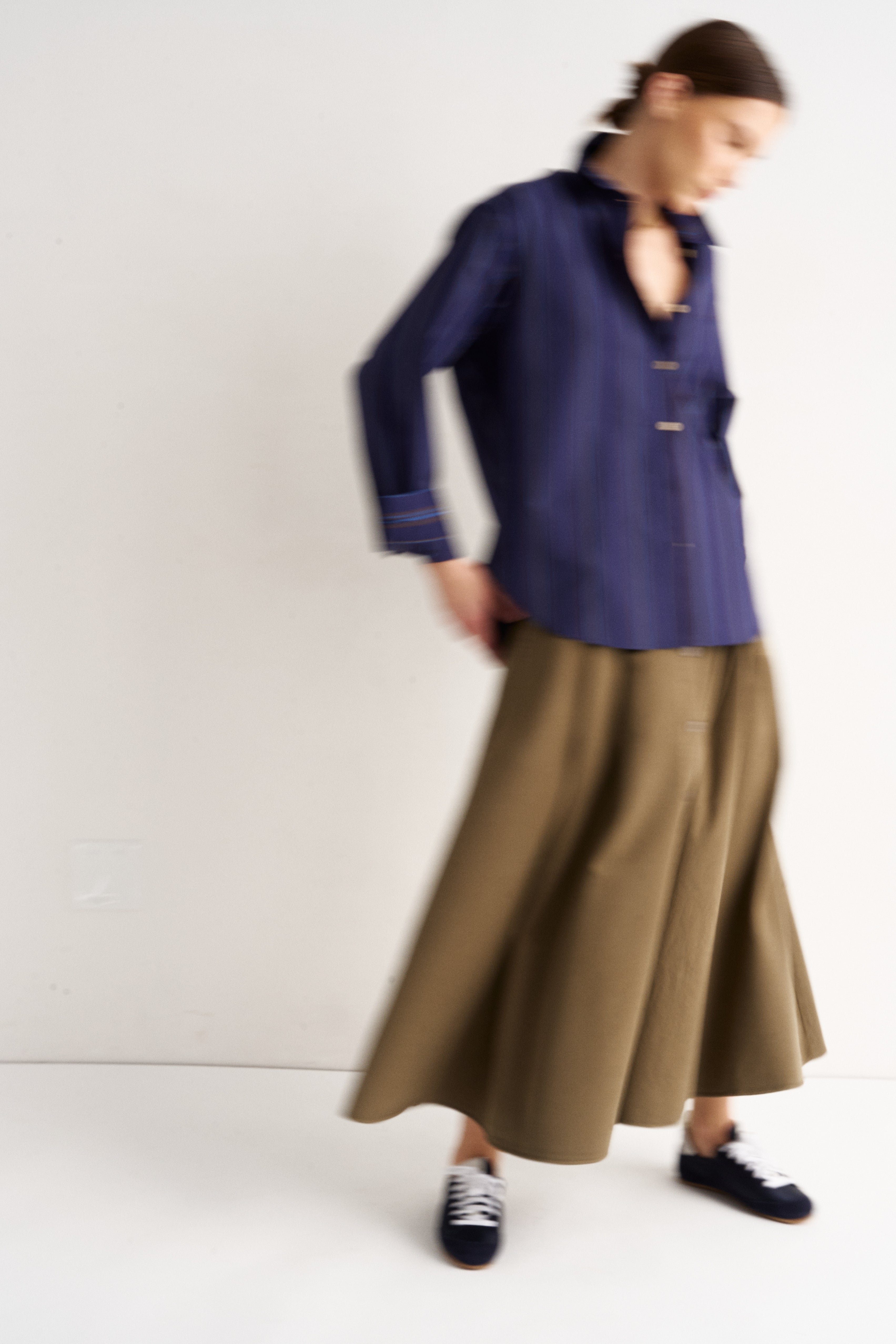 Person wearing a blue shirt and brown skirt on a white background