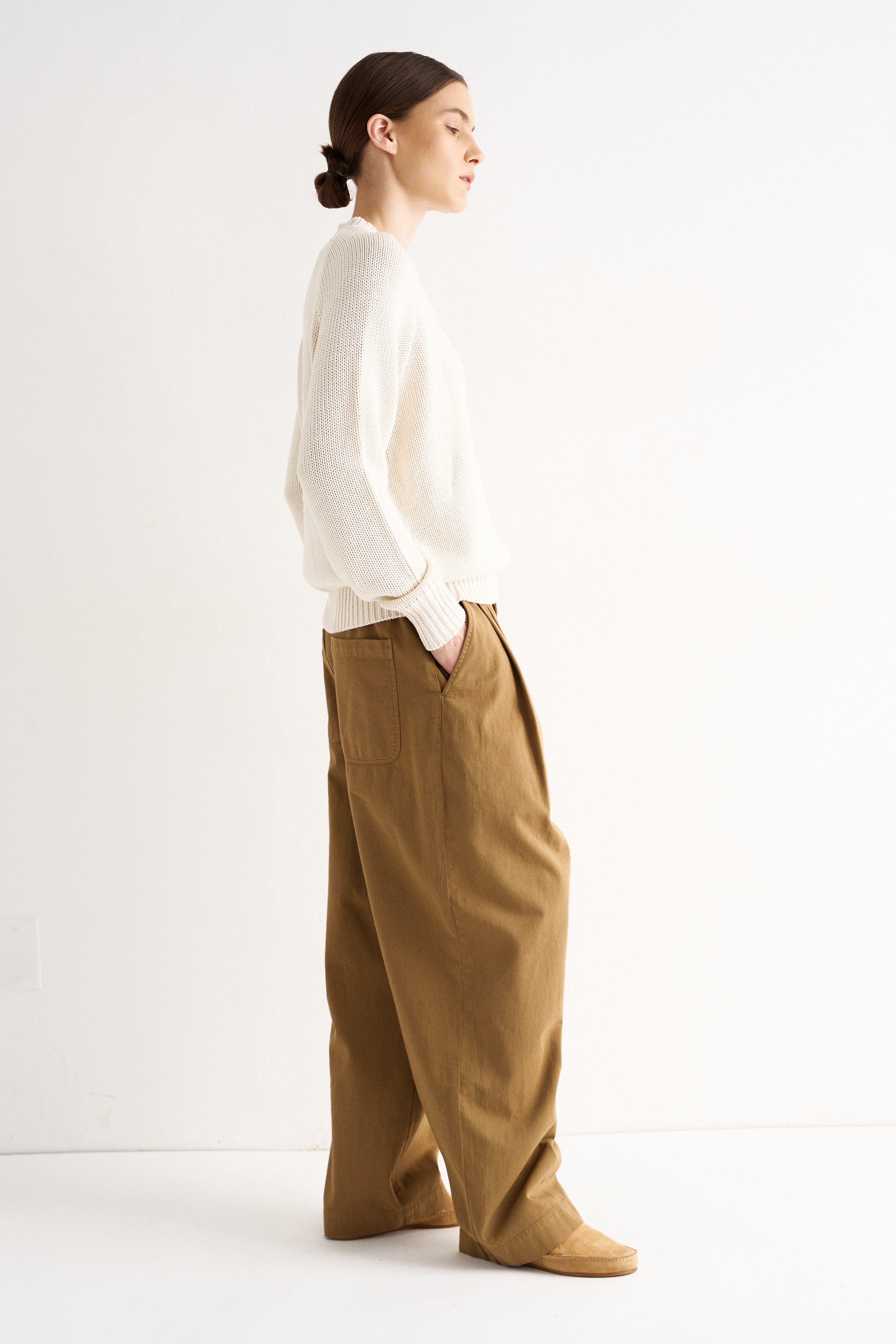 Person wearing a white shirt and brown pants on a white background