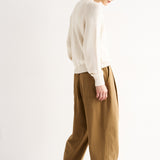 Woman wearing a white sweater and brown pants on a white background