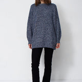woman standing in front of a white will in a crewneck sweater