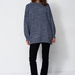 woman standing in front of a white will in a crewneck sweater