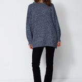 woman standing in front of a white will in a crewneck sweater