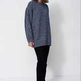 woman standing in front of a white will in a crewneck sweater