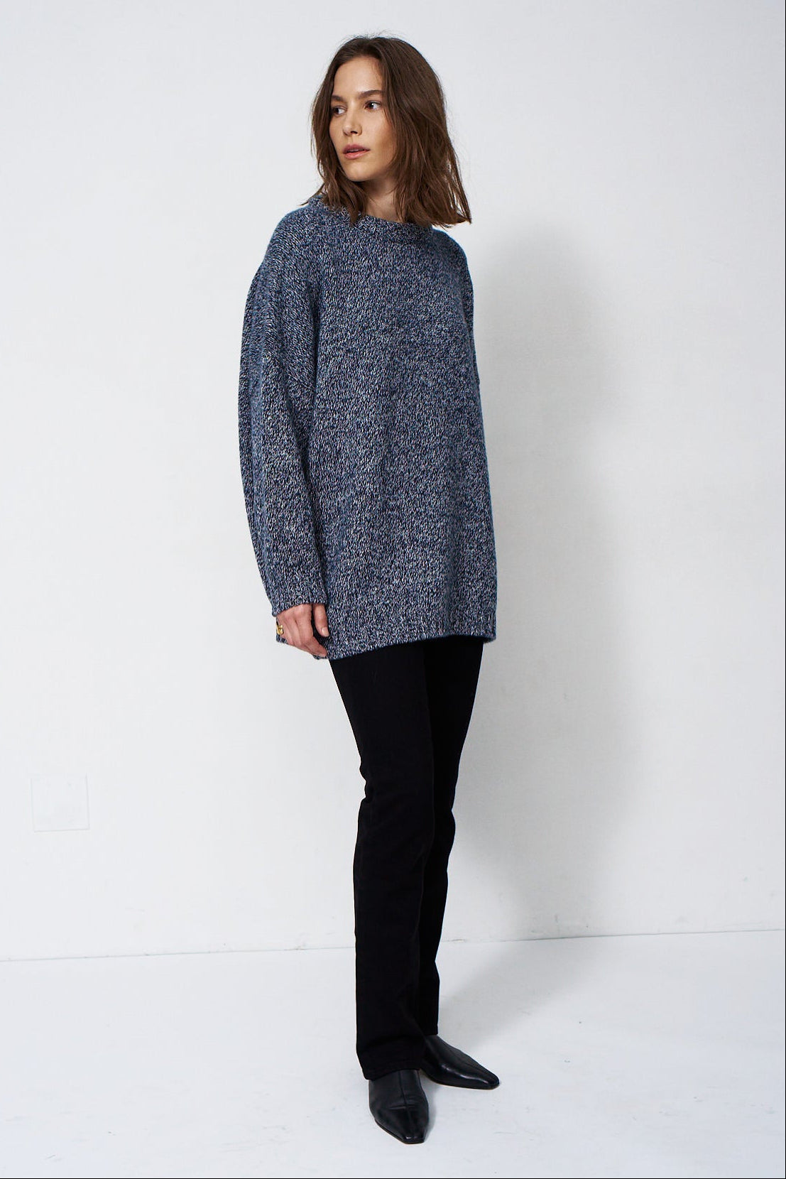 woman standing in front of a white will in a crewneck sweater