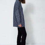 woman standing in front of a white will in a crewneck sweater