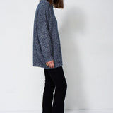 woman standing in front of a white will in a crewneck sweater