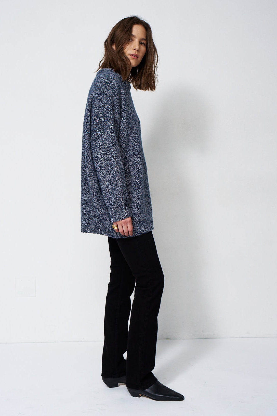 woman standing in front of a white will in a crewneck sweater