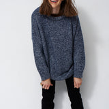 woman standing in front of a white will in a crewneck sweater