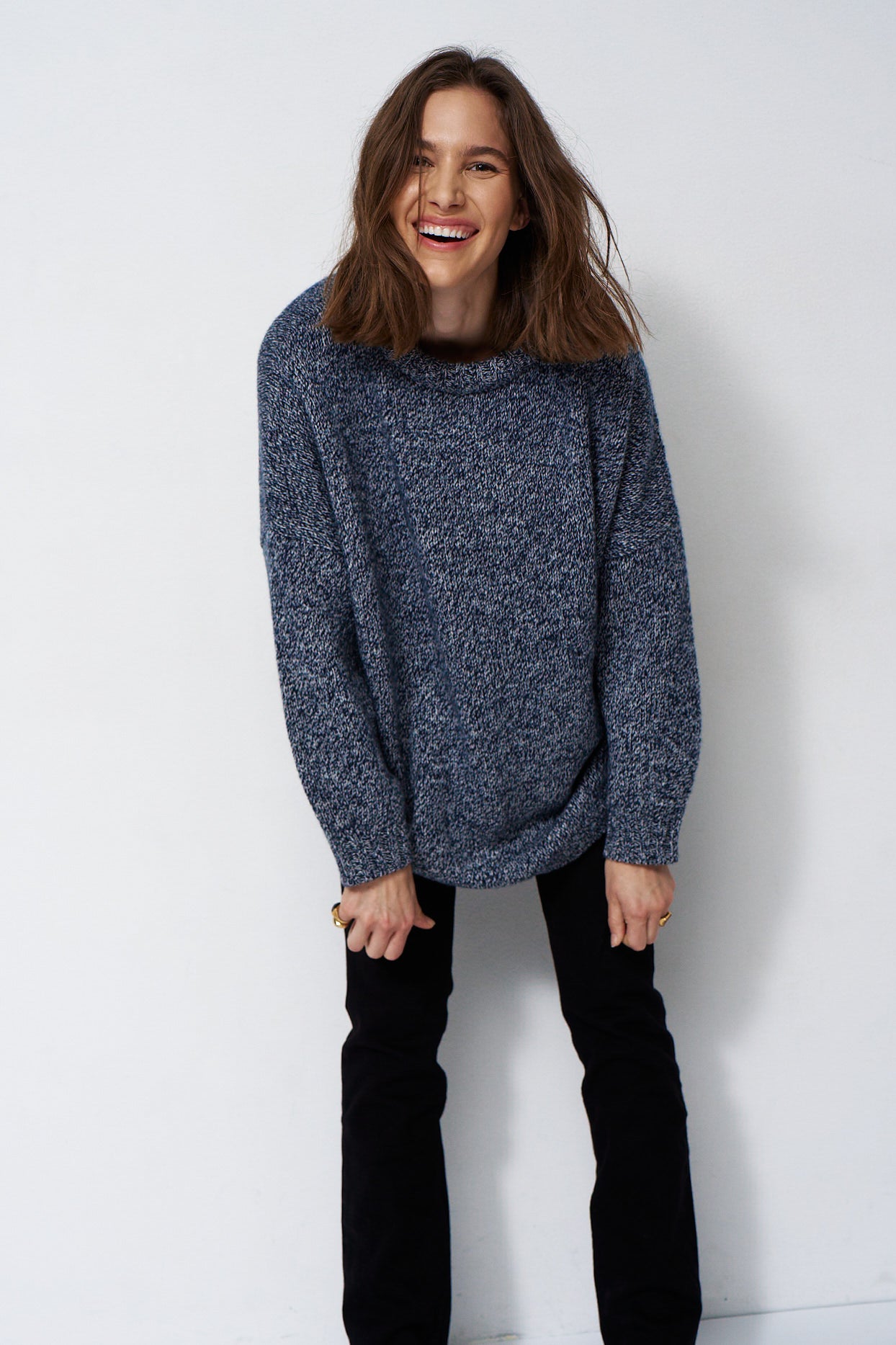 woman standing in front of a white will in a crewneck sweater