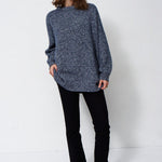 woman standing in front of a white will in a crewneck sweater