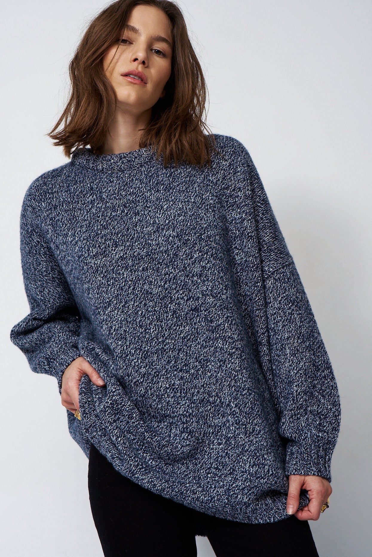 woman standing in front of a white will in a crewneck sweater