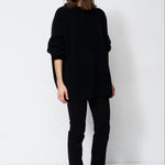 model wearing all black standing in front of a white wall